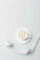 top view of sugar cubes in cup with saucer near retro phone on white