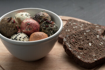 a plate with different colored balls of cheese covered with spices and bread