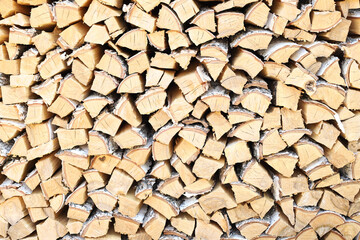 A lot of firewood stacked evenly, texture. Dry birch for furnace. Logs background. Wooden birch logs, bonfire. Closeup, front view.