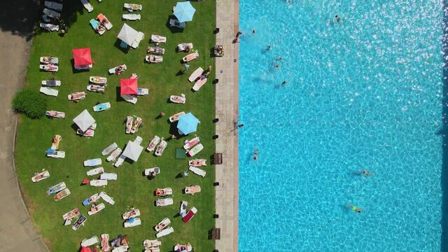 top view of people sunbathing on sun loungers swimming in public city pool