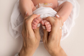 hands of parents. the legs of the newborn in the hands of mom and dad. baby's legs in his hands. 