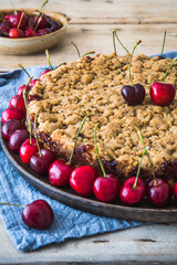 Cherry pie with sprinkles, cherry crumble, and fresh cherries on a rustic wooden background, vertical