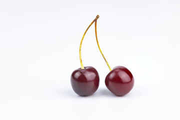 Two ripe cherries with a branch on a white background