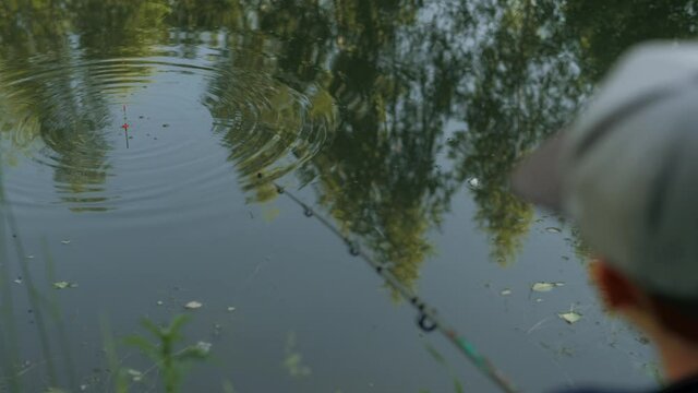 Enthusiastic little male kid catching fish pulling fishing rod with empty hook closeup back view