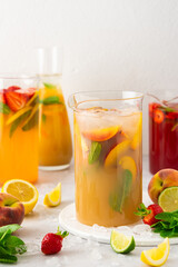 Jugs of fresh refreshing fruit drinks with fruit wedges, summer cold juices with ice
