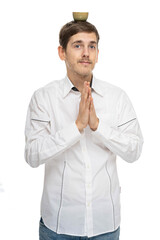 Young handsome tall slim white man with brown hair praying with tea cup on his head in white shirt isolated on white background