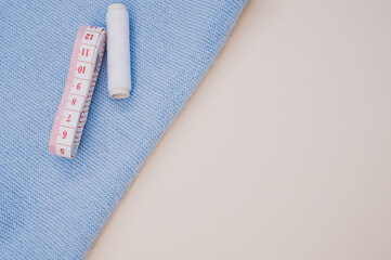 Closeup of a white sewing thread and a measuring tape on the fabric on the brown surface