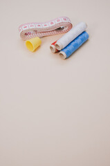 Closeup of the colorful  sewing threads with a thimble and a measuring tape on the brown surface