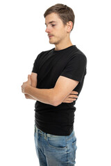 Young handsome tall slim white man with brown hair with crossed arms turned sideways in black shirt in blue jeans isolated on white background