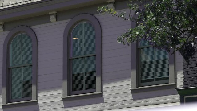 An establishing shot of apartment windows above a small business on the main street of a small town.  	