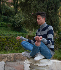 A young Hispanic male doing yoga and meditating in the park
