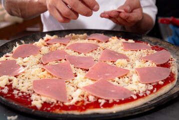 putting some ham in the pizza 