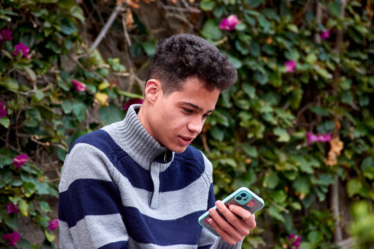 A portrait of an attractive Hispanic male using his smartphone in the park