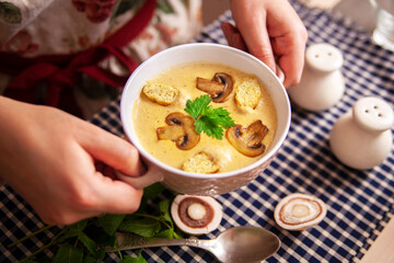 Hands with mushroom soup in the plate