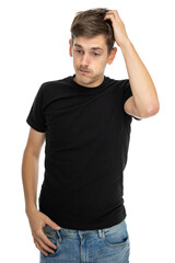 Young handsome tall slim white man with brown hair scratching his head in black shirt in blue jeans isolated on white background