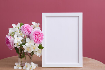 Empty white frame mock up with flowers on pink background. Temlate for your text or picture
