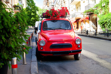 Red retro car with a red flowers in the street