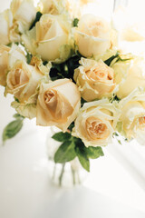 Obraz na płótnie Canvas bouquet of cream roses in a transparent vase