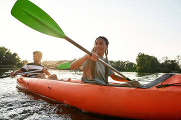 Sportive young couple, boyfriend and girlfriend having fun on kayak on a summer afternoon