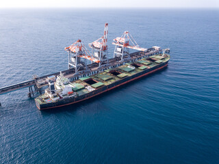 Bulk container ship unloads coal in the port of power station.