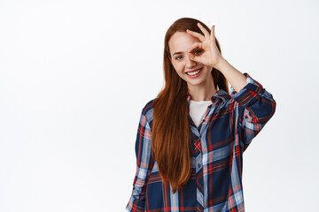 Zero problems. Smiling cute ginger girl with long natural hair, shows okay OK sign and look...