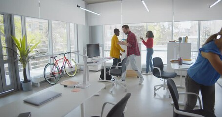 Diverse employees in casual wear sitting down at workplaces in open space office