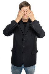 Young handsome tall slim white man with brown hair covers his eyes in black blazer in blue jeans isolated on white background