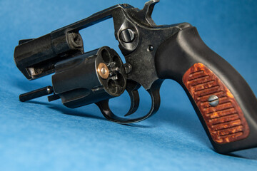 Revolver with one cartridge in the drum on a blue background. Russian roulette. Close-up.