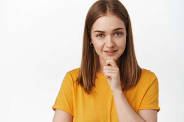 Close up of thoughtful and confident young woman, looking interested and self-assured at camera,...