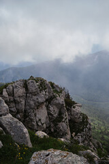 Nature and landscape of national Park in Caucasus. Cold summer day in mountains. Steep rocky mountain against background of thick black fog before rain.