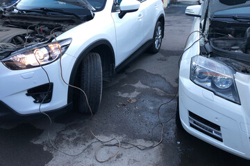 Charging of car battery from another car charger with long wires, assistance with engine starting, mutual aid concept.