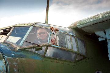 A middle-aged man with a dog aboard an old abandoned Soviet plane. The man looks out the window.