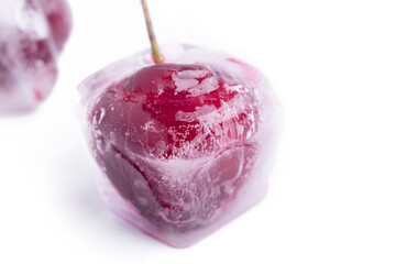 the background is white. Red cherries in ice cubes. Close-up. Macro.
