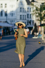 Woman with phone and hat walking in the city