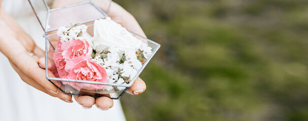 Bride holding wedding box for rings with white and pink flowers