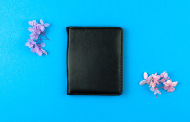Black leather notebook with dried flowers on a blue desktop background, flat lay and top view photo