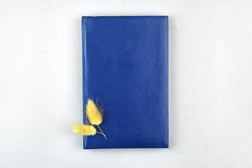 Minimal workspace mockup with blue leather notepad and dry dried flowers, office desktop top view photo