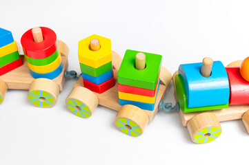 Wooden train with colored blocks on white background. Kids toys made of natural wood in rainbow colors. Eco friendly toy, game, plastic free. Toy for babies and toddlers. Flat lay side view