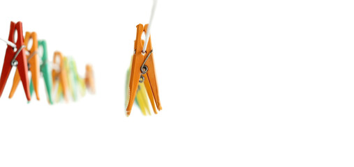 Multicolored clothespins for drying clean washed clothes hang on a clothesline on the side on a...