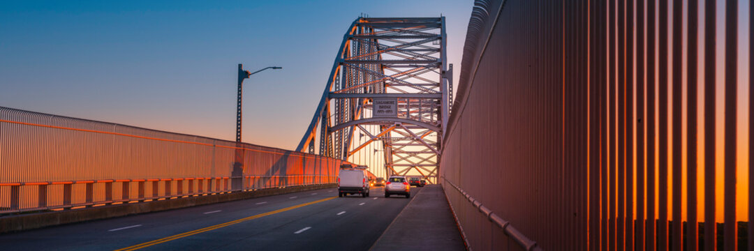 Sagamore Bridge at Sunrise over Cape Cod Canal. Glowing Gold Silhouette Architectural Image. High Contrast Panoramic Backdrop with Space for Text and Design.