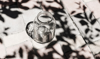 Empty glass jar outdoors. Reusable tableware with tree leaf shade. Taking care of the environment, avoiding plastic and zero waste.