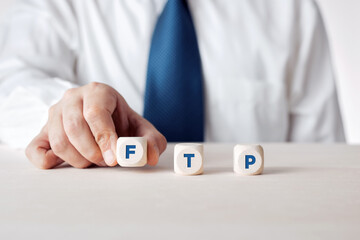 Businessman placing the wooden cubes with the word FTP file transfer protocol.