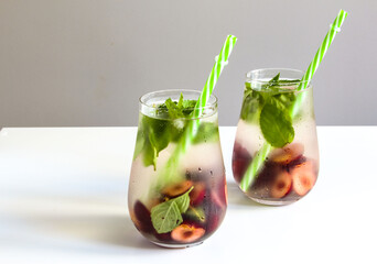 Cold drinks in small bottles. Cherries and mint lemonade. Mojito coctail. Summer iced refreshment drink. Summer cold mint coctails with berries. Mason jar glass with cold drink.