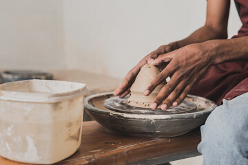 partial view of young african american man modeling wet clay on wheel in pottery