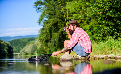 Fototapeta na wymiar fly fish hobby. Summer activity. successful fisherman in lake water. mature bearded man with fish on rod. big game fishing. relax on nature. hipster fishing with spoon-bait. The Old Man and the Sea