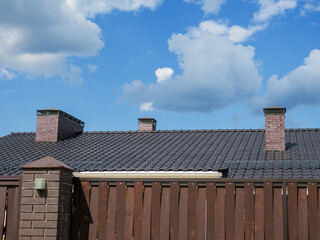 A fragment of a metal-tile roof with three chimneys.