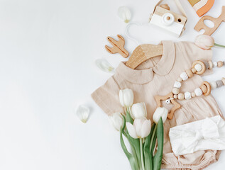 Summer baby clothes on white background, fashion newborn concept, neutral bodysuit with tulips and eco friendly toys. Top view - 441469667