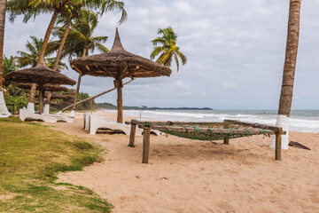 Axim beach with coconut palm trees and sunbeds lying on the gold coast of Ghana West Africa.