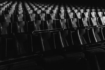 a ray of light illuminates an empty cinema. The chairs in the cinema hall are illuminated by a beam of light, a low key. Selective focus. Leisure vacation concept