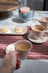 Closeup view of a woman hand holding an elegant pink cup of bubbled coffee in a relaxing pink breakfast.